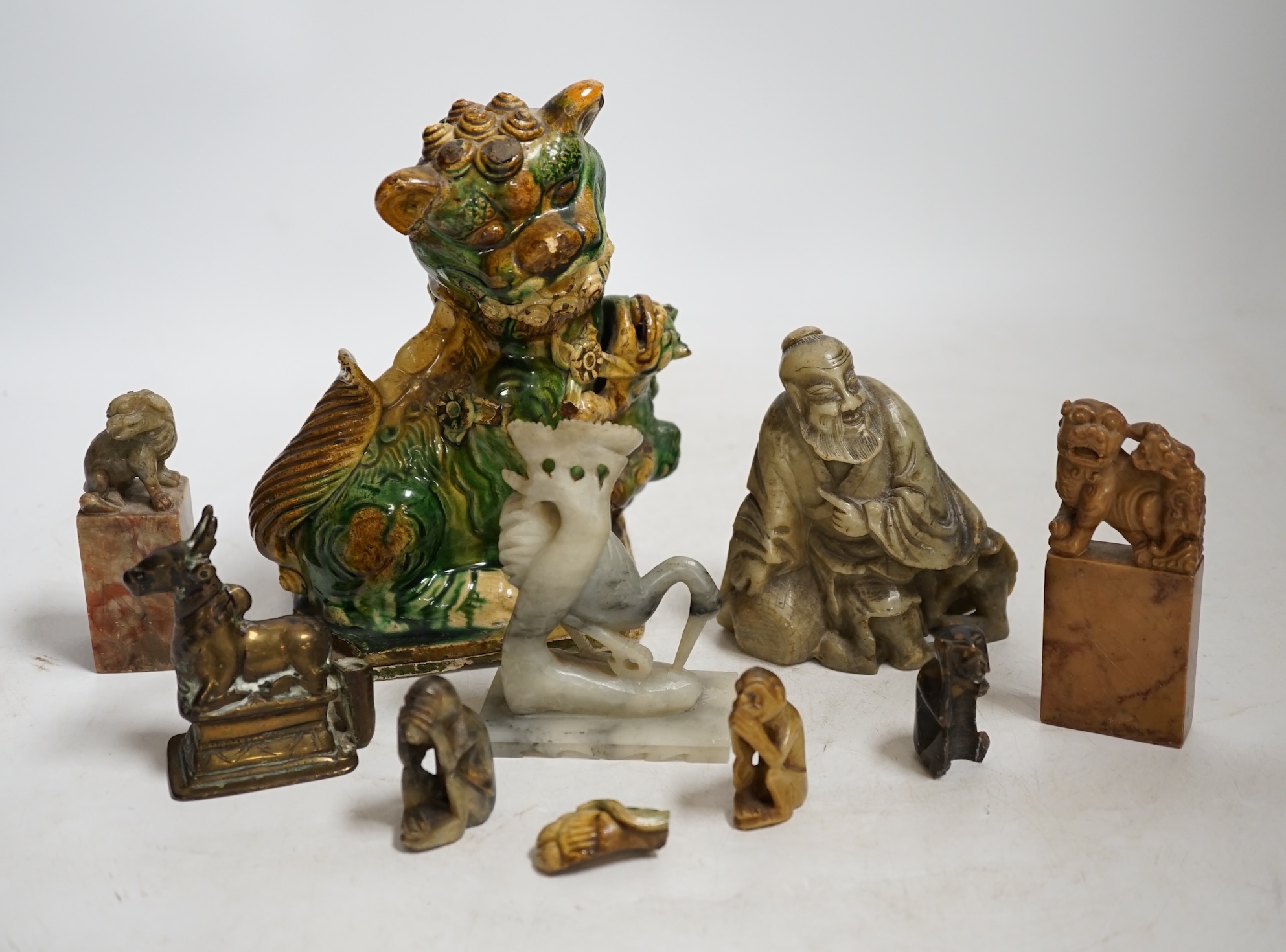A glazed Chinese lion dog and a collection of soapstone carvings including seals, largest 17cm high. Condition - varies, poor to fair